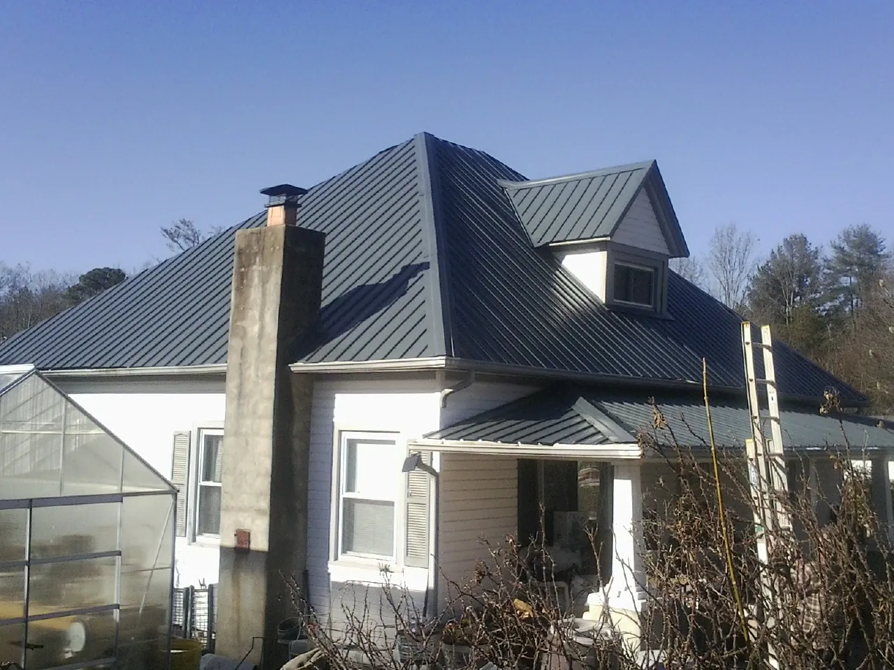 Dark blue standing seam metal roof on a white farmhouse with dormer — Slate & Tile Roof Repair by Roofing Brothers in Reedsville