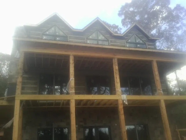 Dormers and porch framing on a large log home under construction — Roof Coating work by our crew in Reedsville