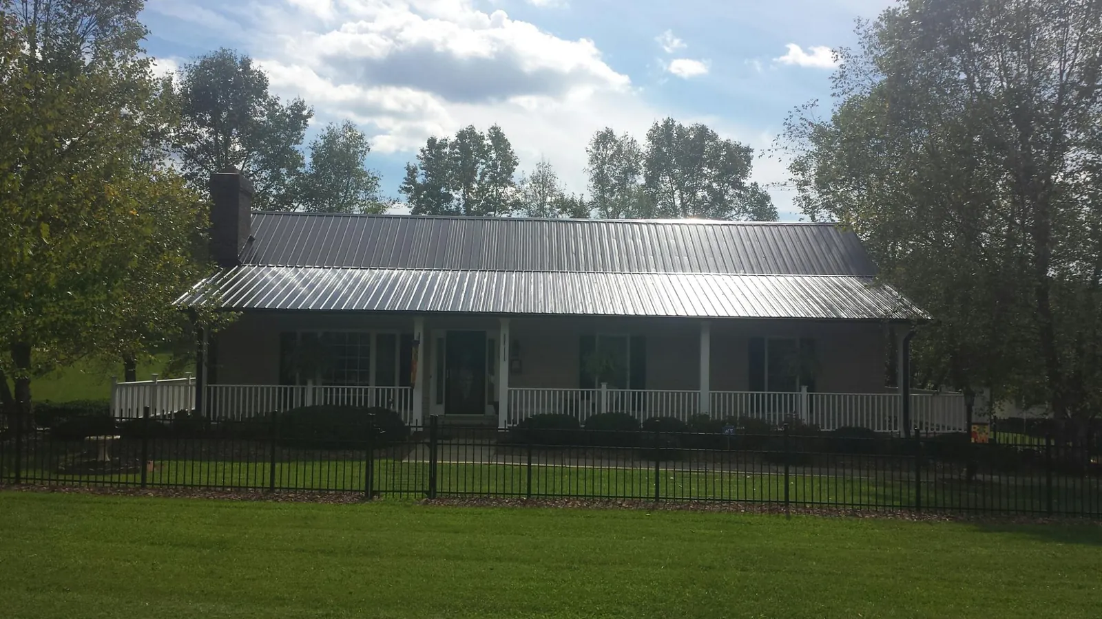 Gray metal roof on a brick ranch with a full width front porch — Gutter Guard Installation work by our crew in Reedsville